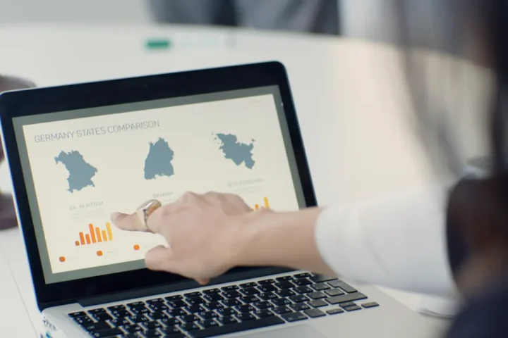 person pointing at a laptop with side-by-side comparison charts